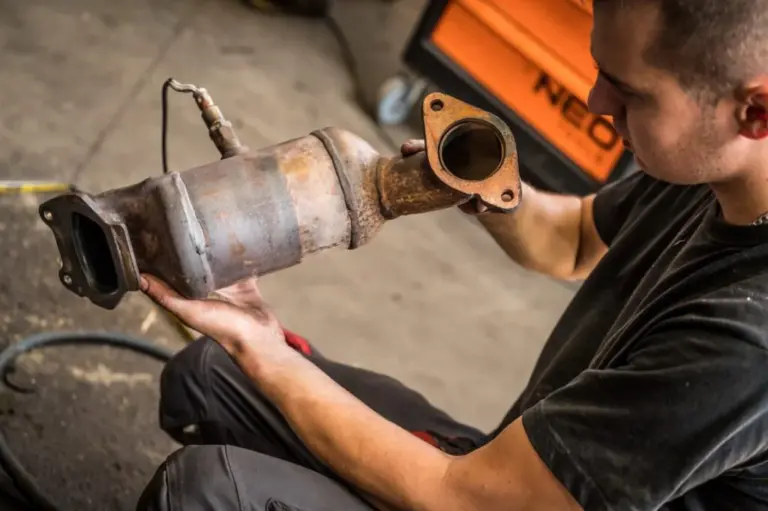 Mechaniker hält einen ausgebauten Dieselpartikelfilter (DPF) in der Werkstatt zur Sichtprüfung von Ein- und Auslass.